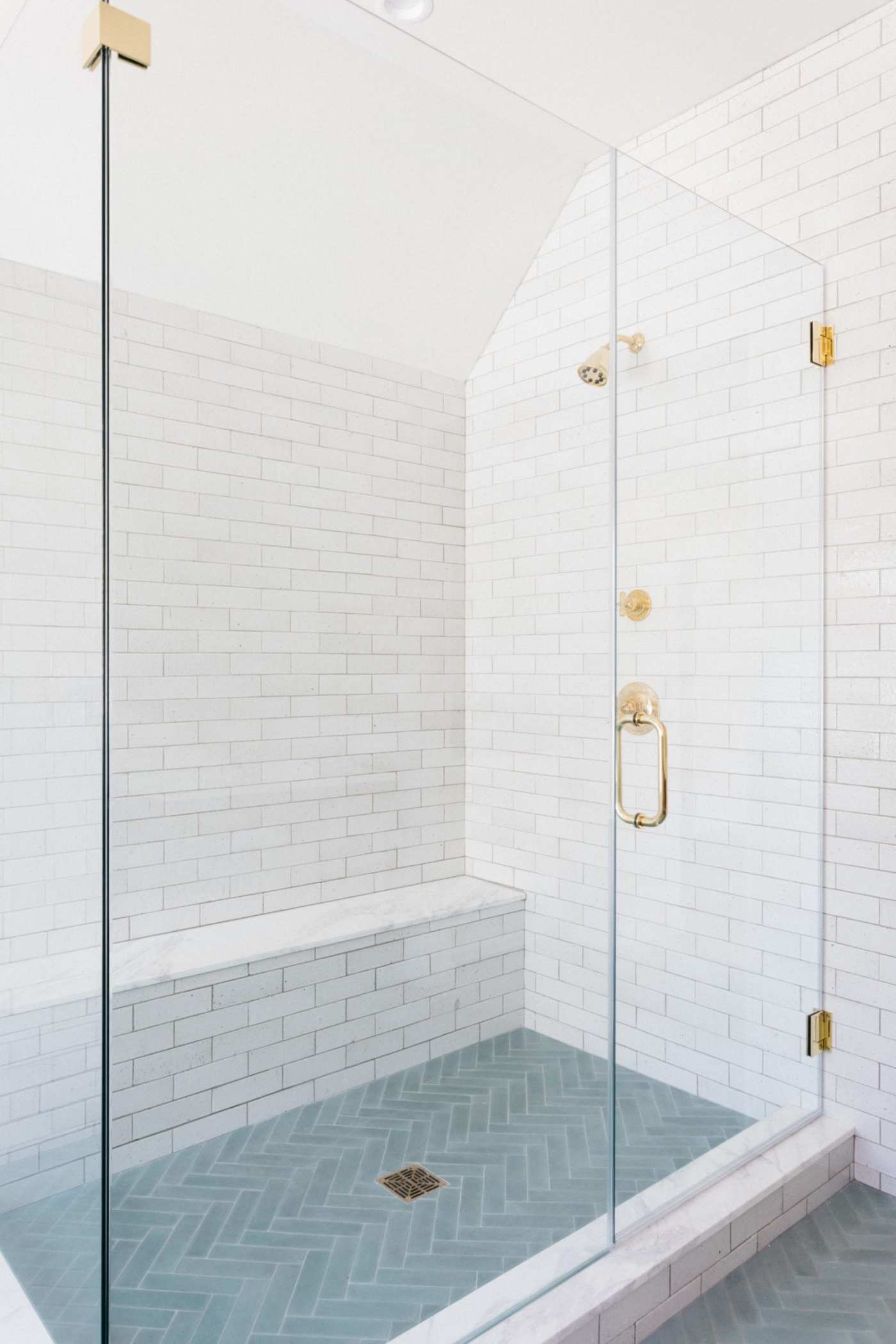 a tiled shower with a blue floor, white walls and a glass door.