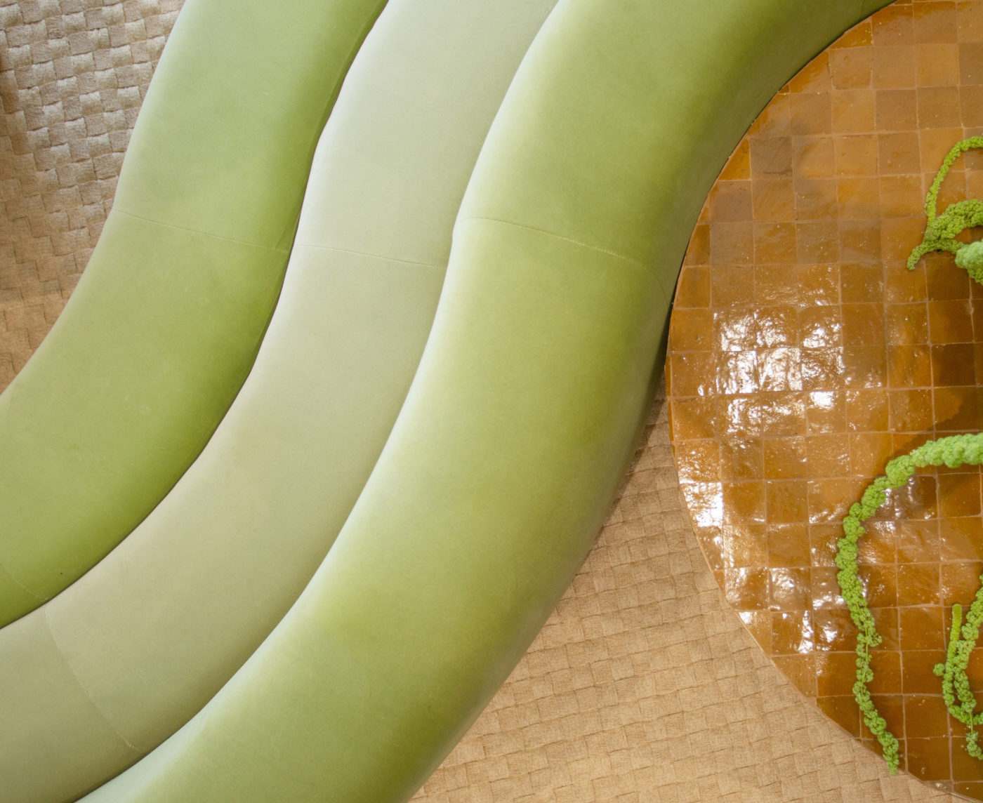 a green couch next to a round tiled table.