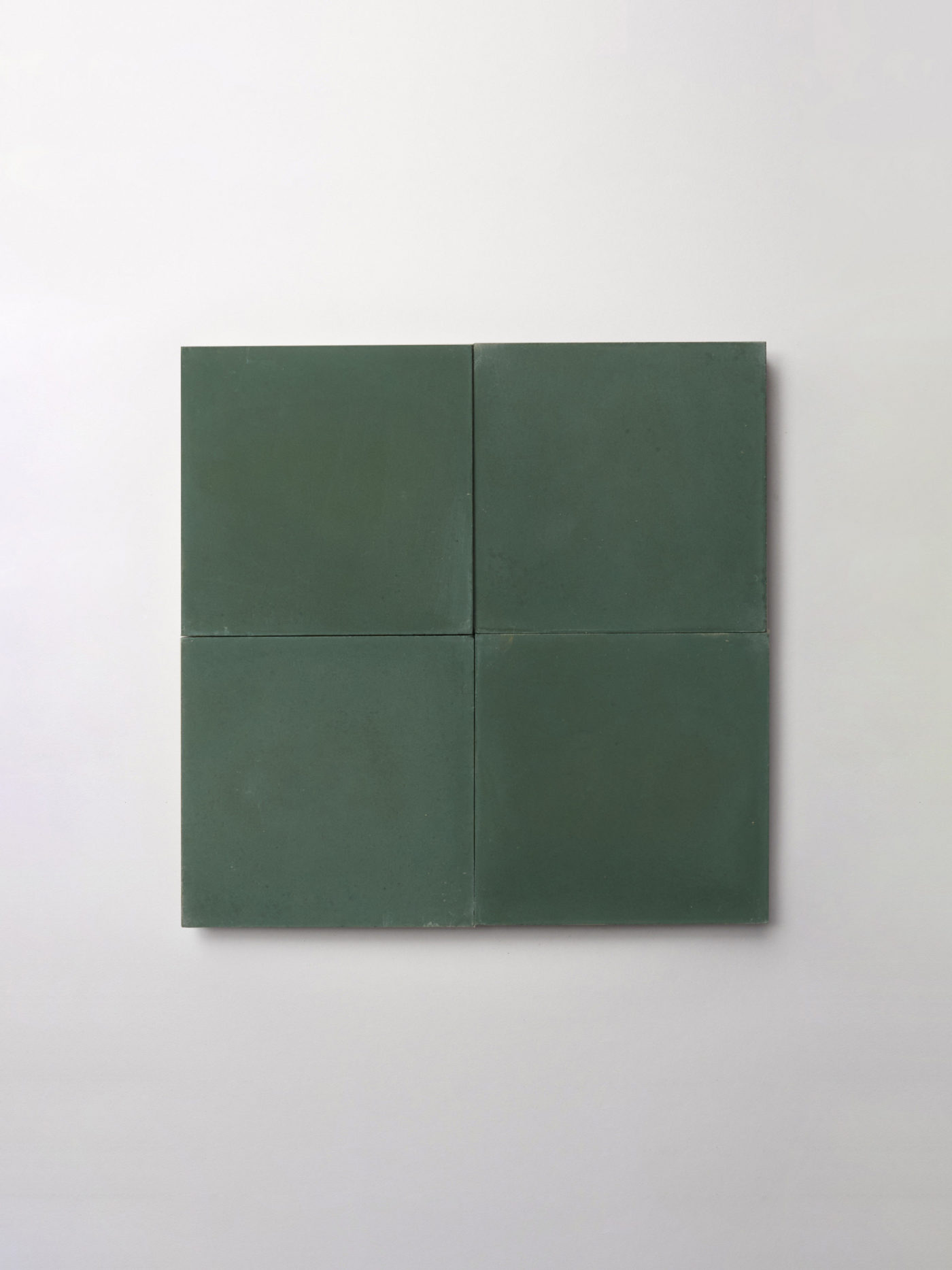 four square green tiles on a white surface.