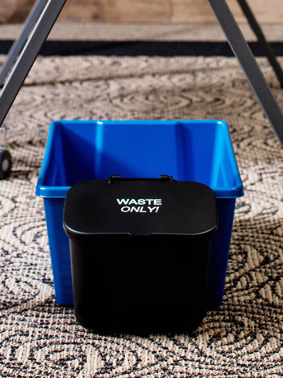 small waste container for hanging on the side of a deskside recycling bin sitting on the floor in a home office
