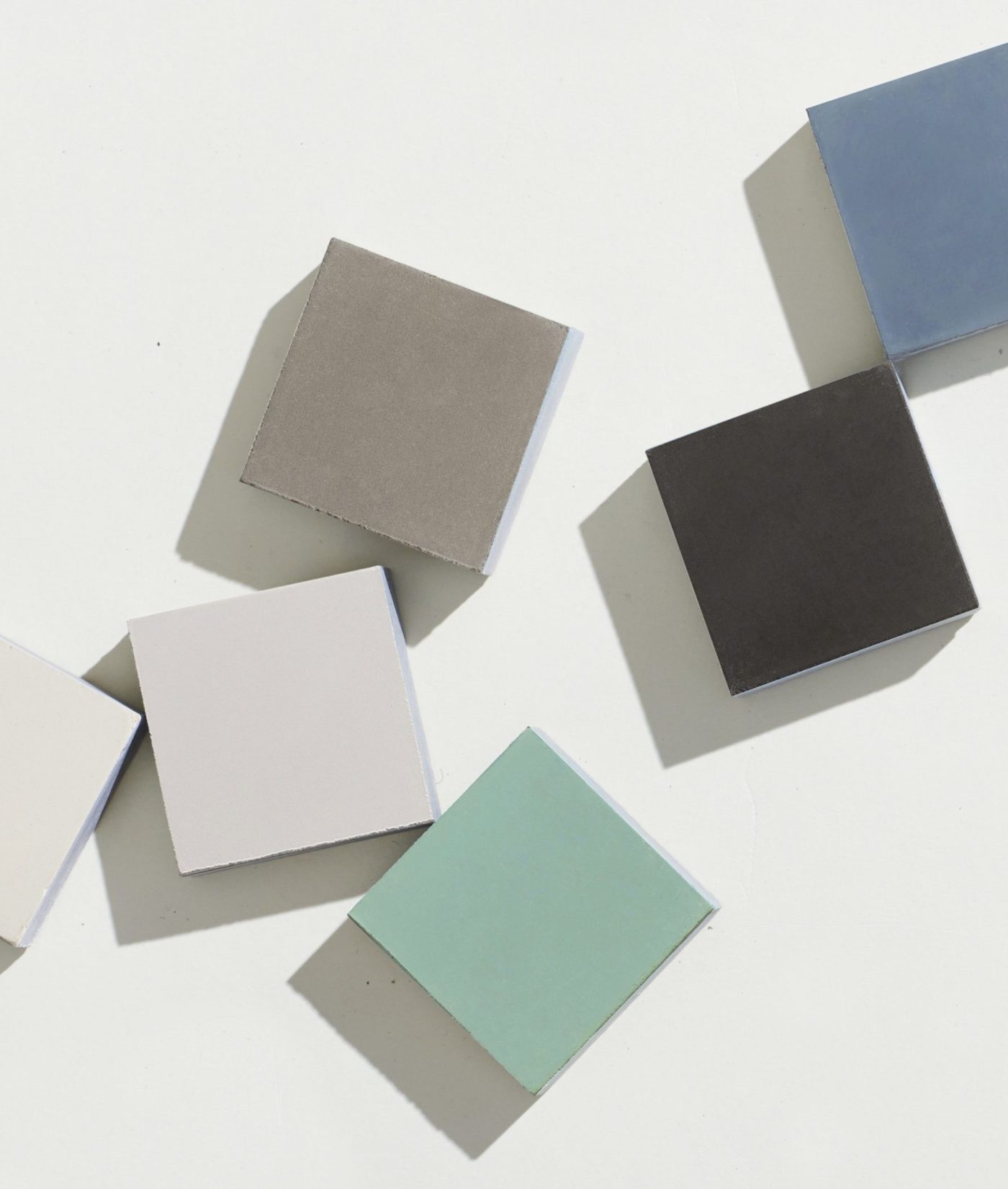 a group of different colored square tile chips scattered on a white surface.