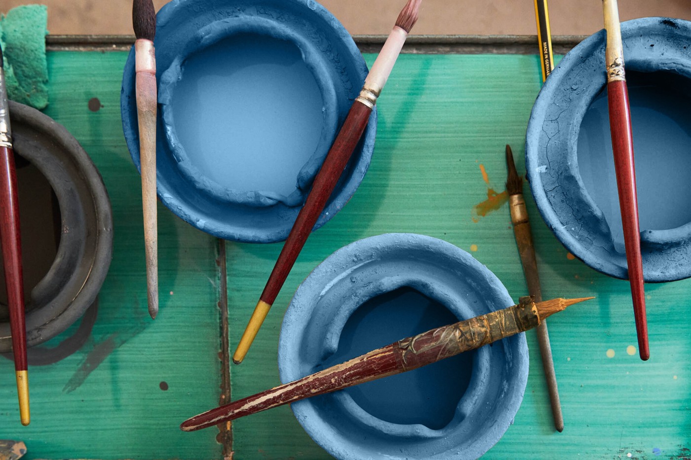 a group of paint brushes and bowls on a table.