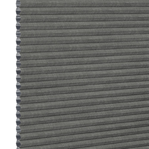 Gray honeycomb (cellular) fabric blind, fully lowered with visible hexagonal cells along the left edge; blocking light, shown in an even, neutral close-up product background.