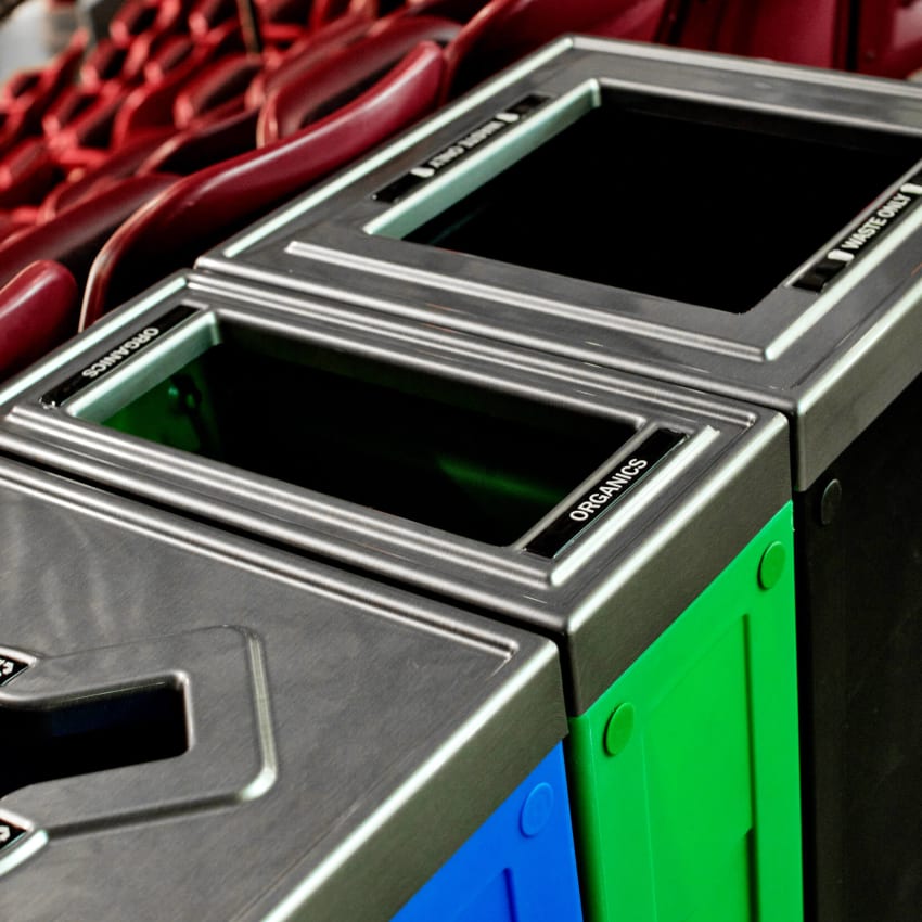 closeup of recycling organics and waste container lids with brushed pewter finish located in a hockey arena