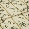 Folded fabric sample in cream background with linear print of bamboo shoots and leaves.