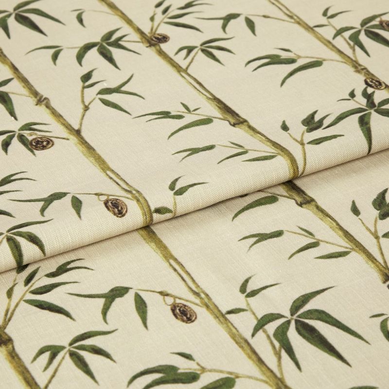 Folded fabric sample in cream background with linear print of bamboo shoots and leaves.