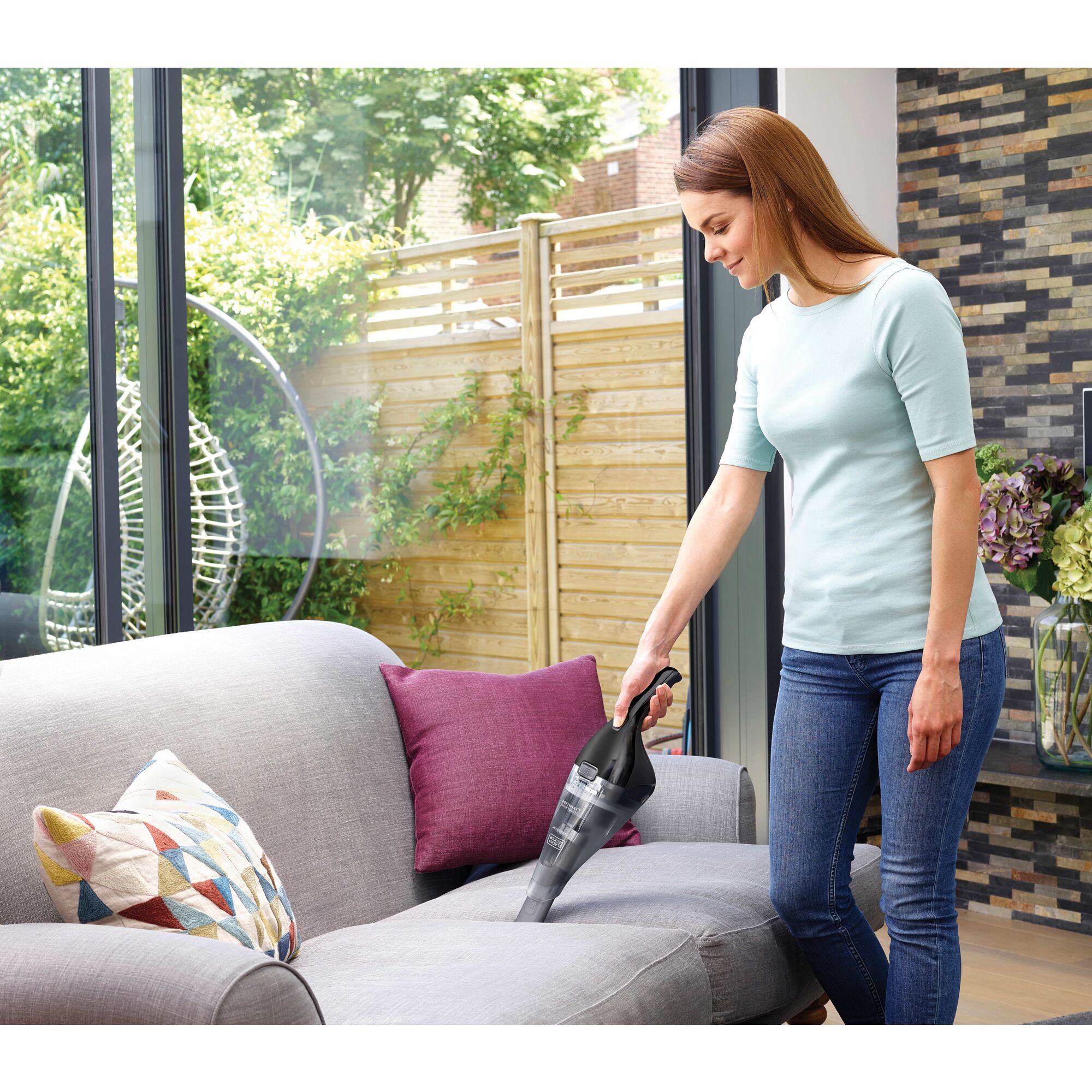 dustbuster QuickClean cordless hand vacuum being used by a person to clean couch.