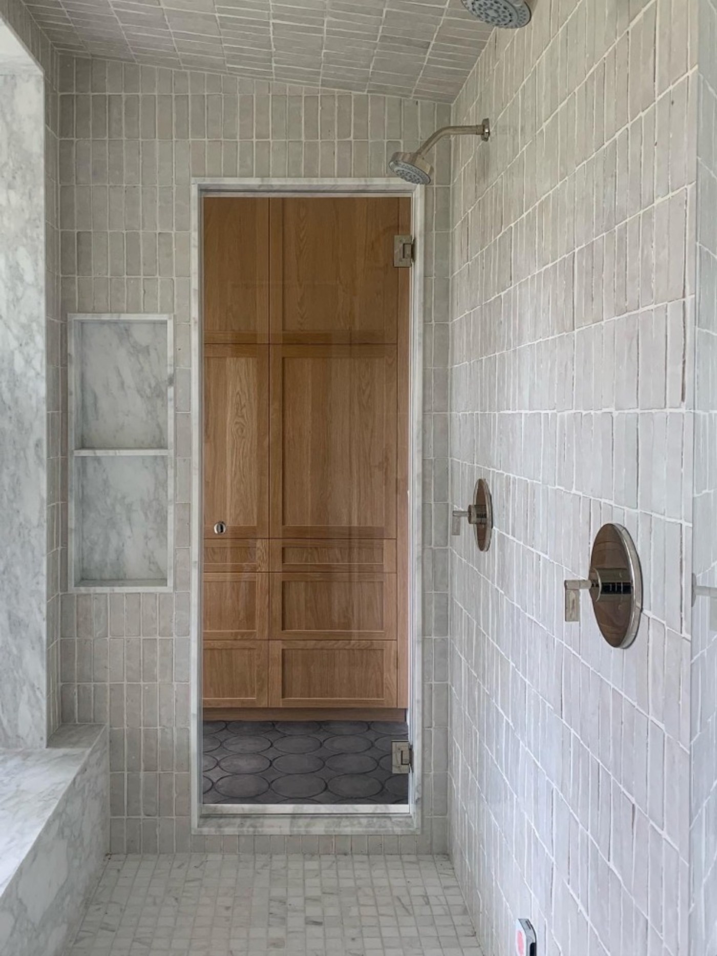 a white tiled shower with a glass door.