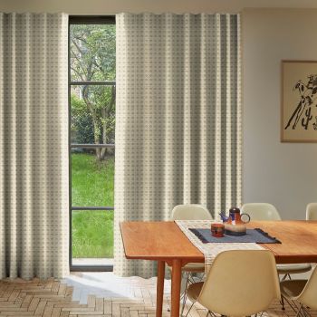 Patterned beige curtains, mostly drawn with a narrow central opening filtering daylight; covering a tall multi‑pane window overlooking a green yard, in a dining room with wooden table and chairs.