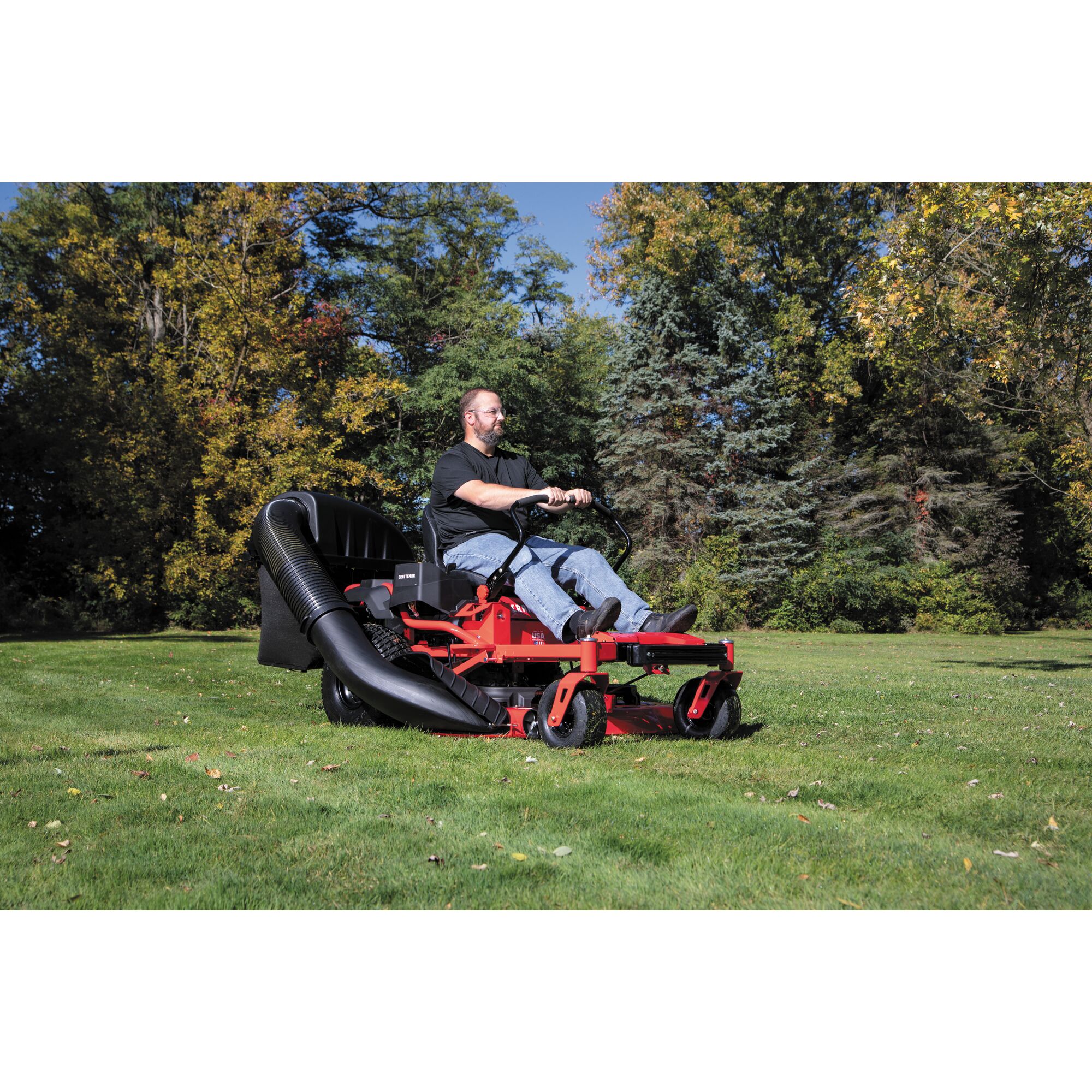 42 inch and 46 inch zero turn double bagger being used to cut grass by person.