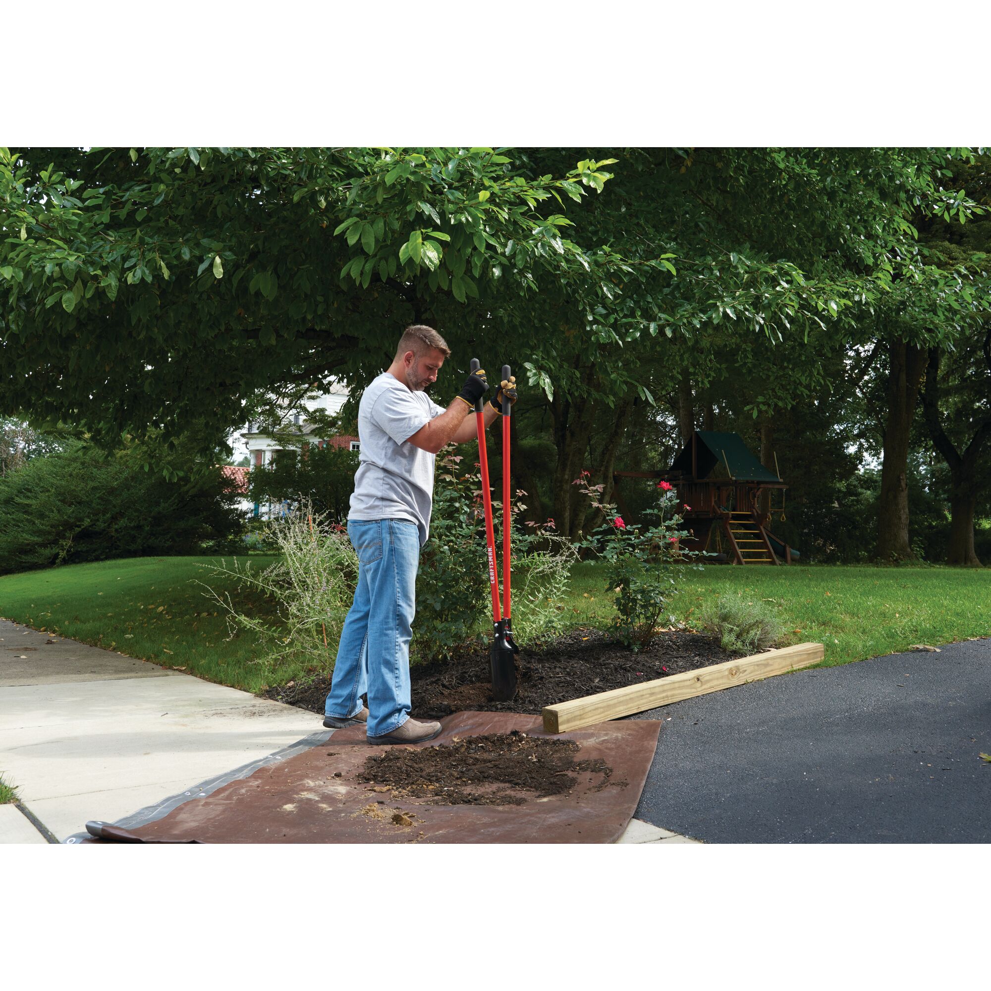 Fiberglass handle post hole digger being used by a person.