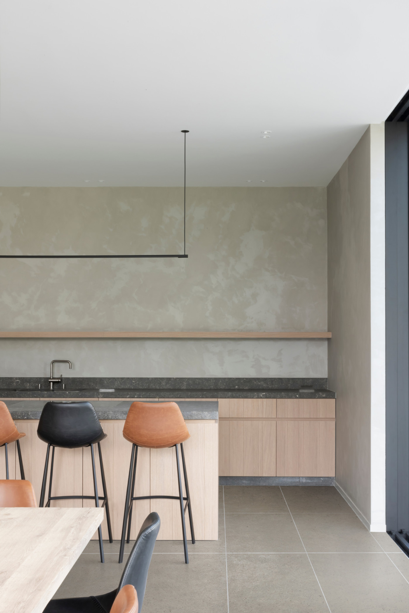 a modern kitchen with a table and brown and black chairs.