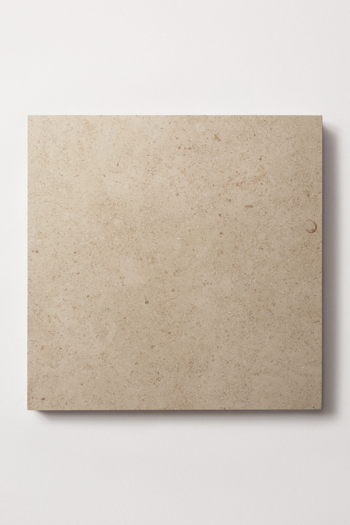 a square beige tile on a white surface.