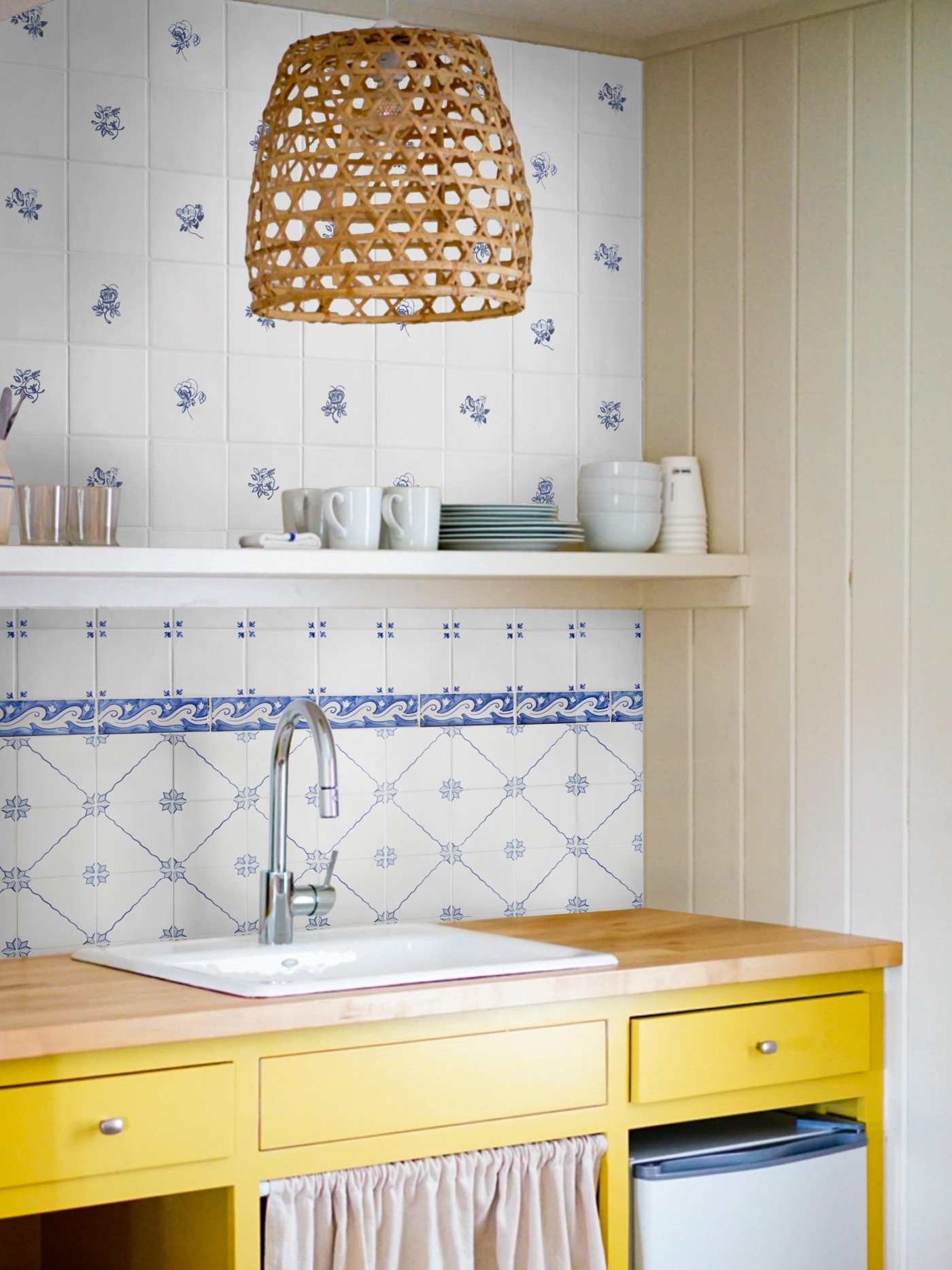 a blue and white kitchen sink backsplash with yellow drawers below.