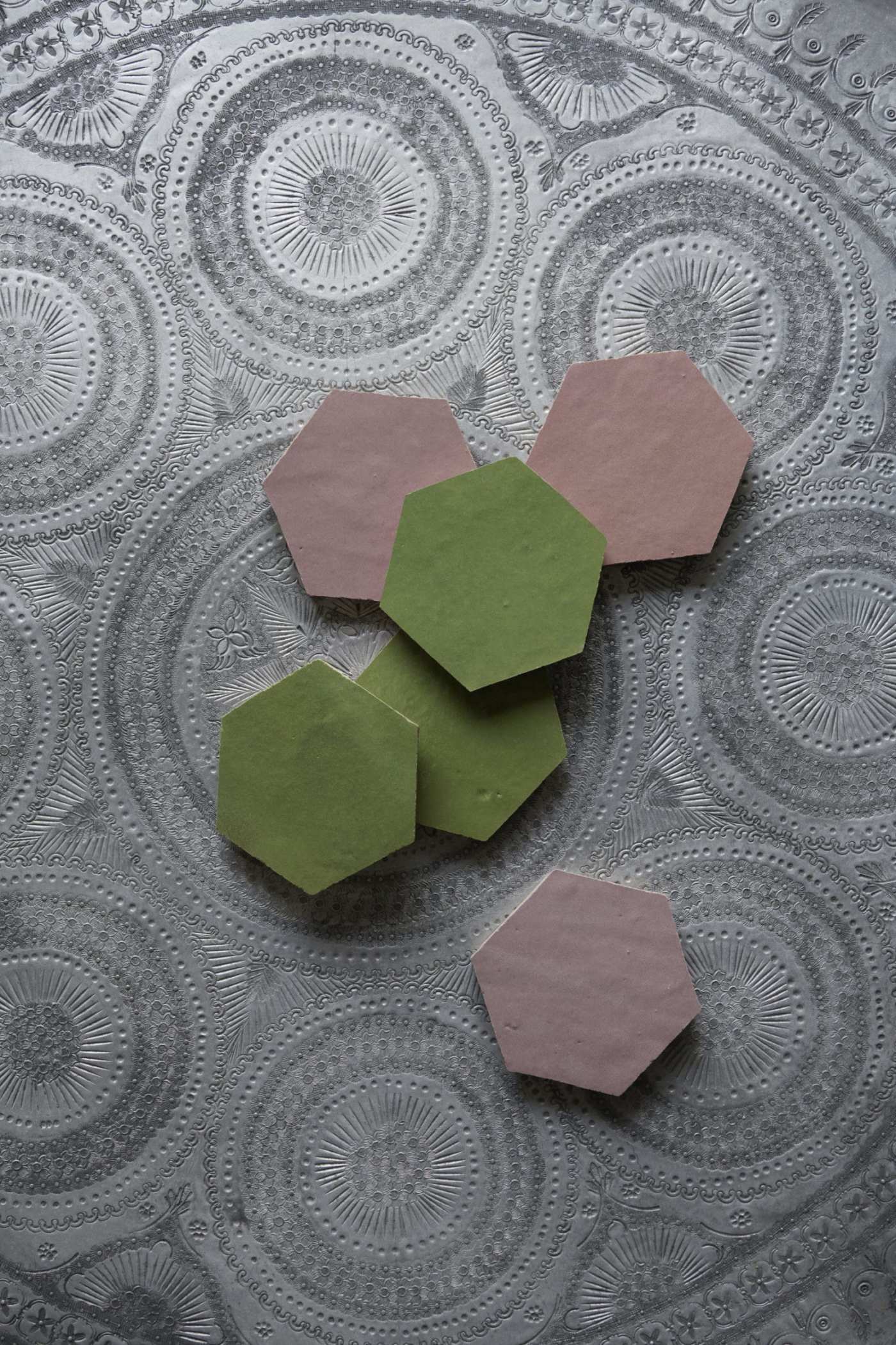 a set of pink and green hexagon tiles on a silver plate.