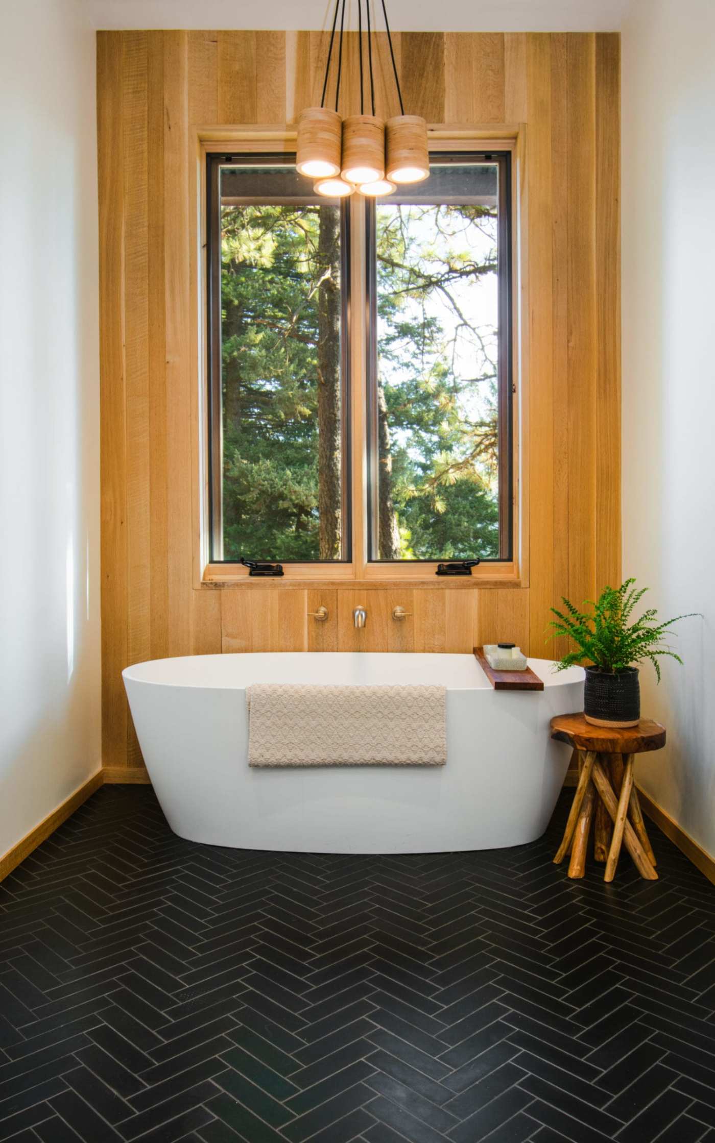 a bathroom with a black tile floor and a wooden wall with a window.