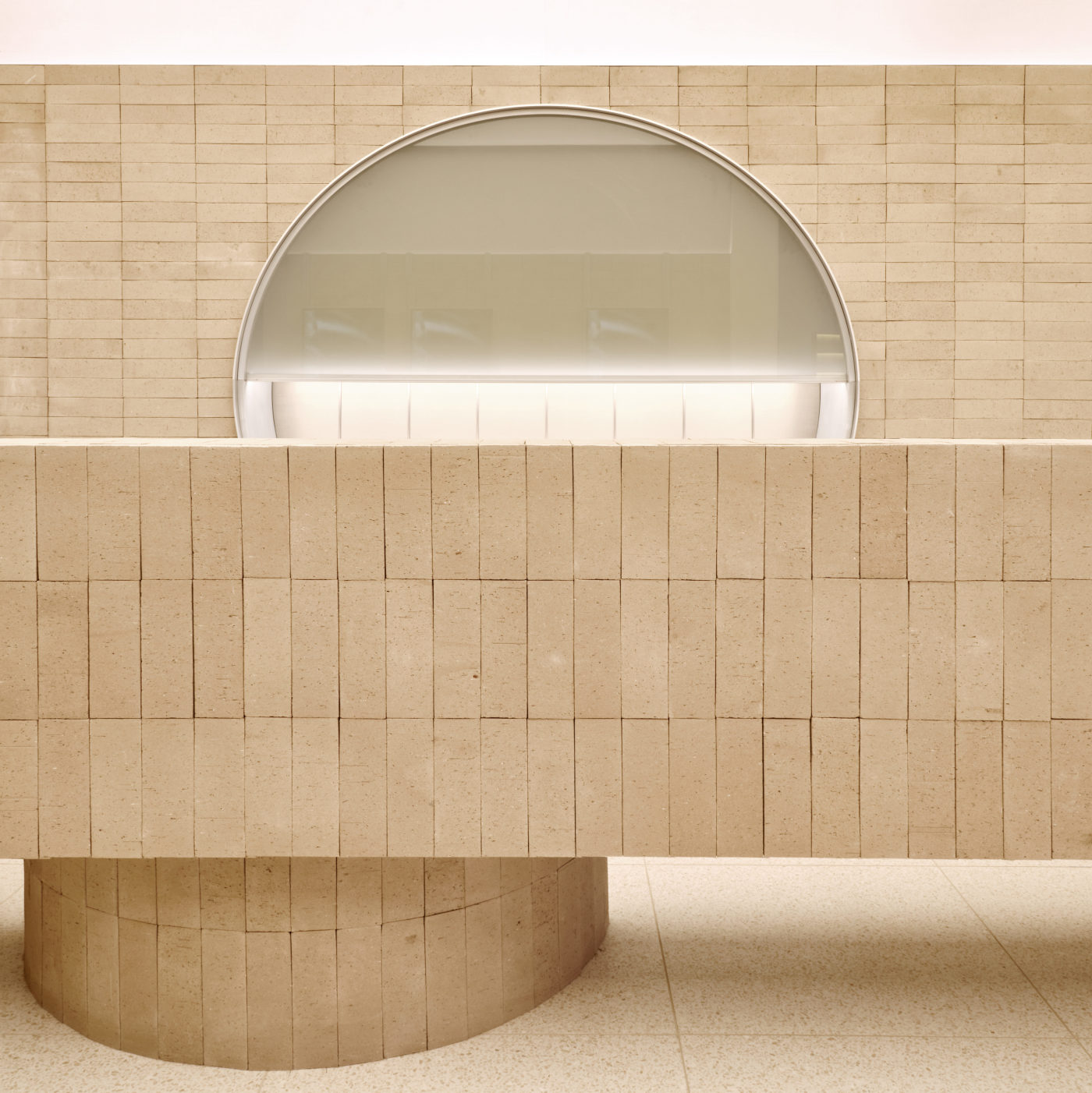 a beige tiled wall with a circular opening in the middle.