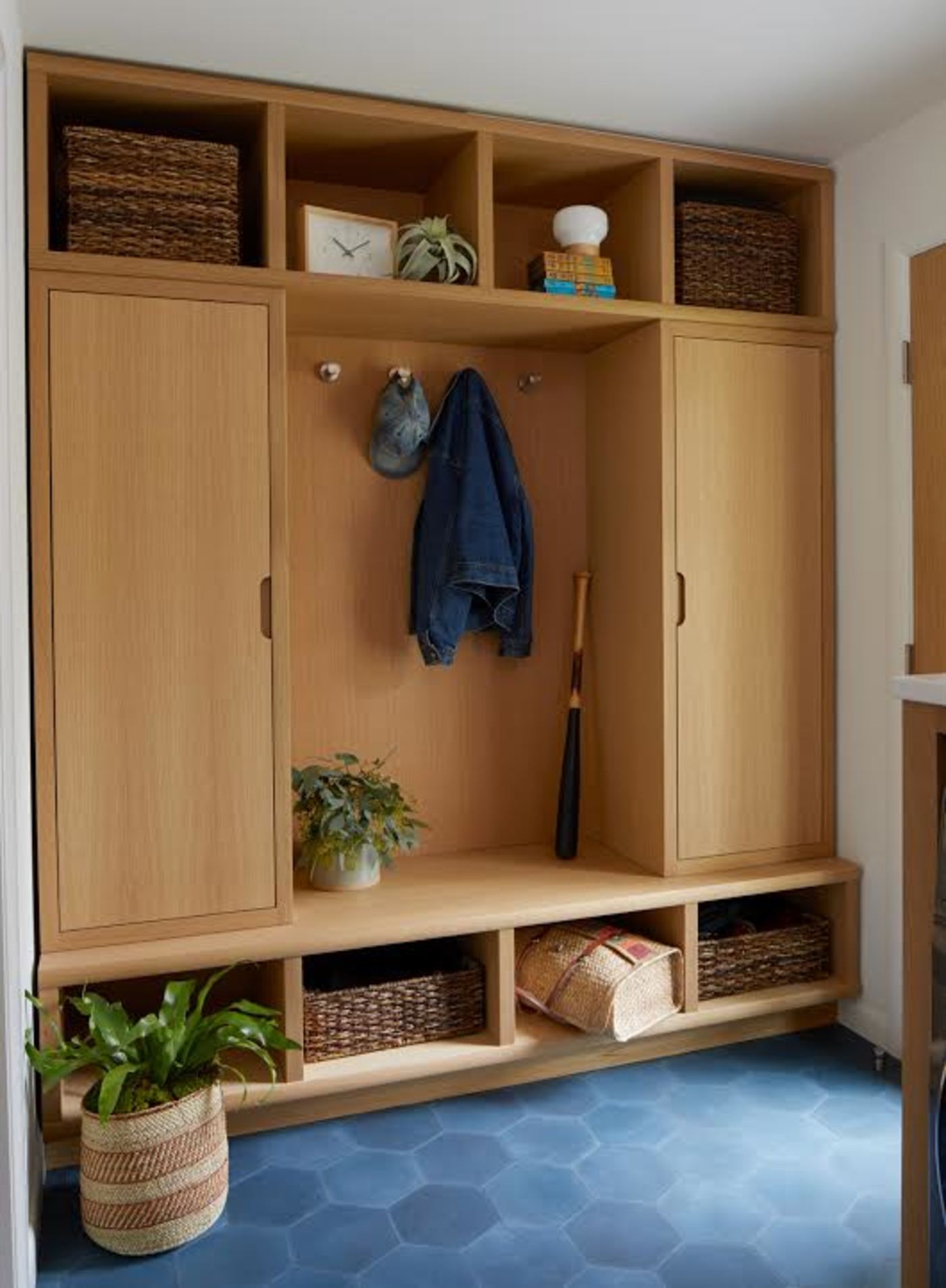 a mudroom with wooden cabinets and a blue tile floor.