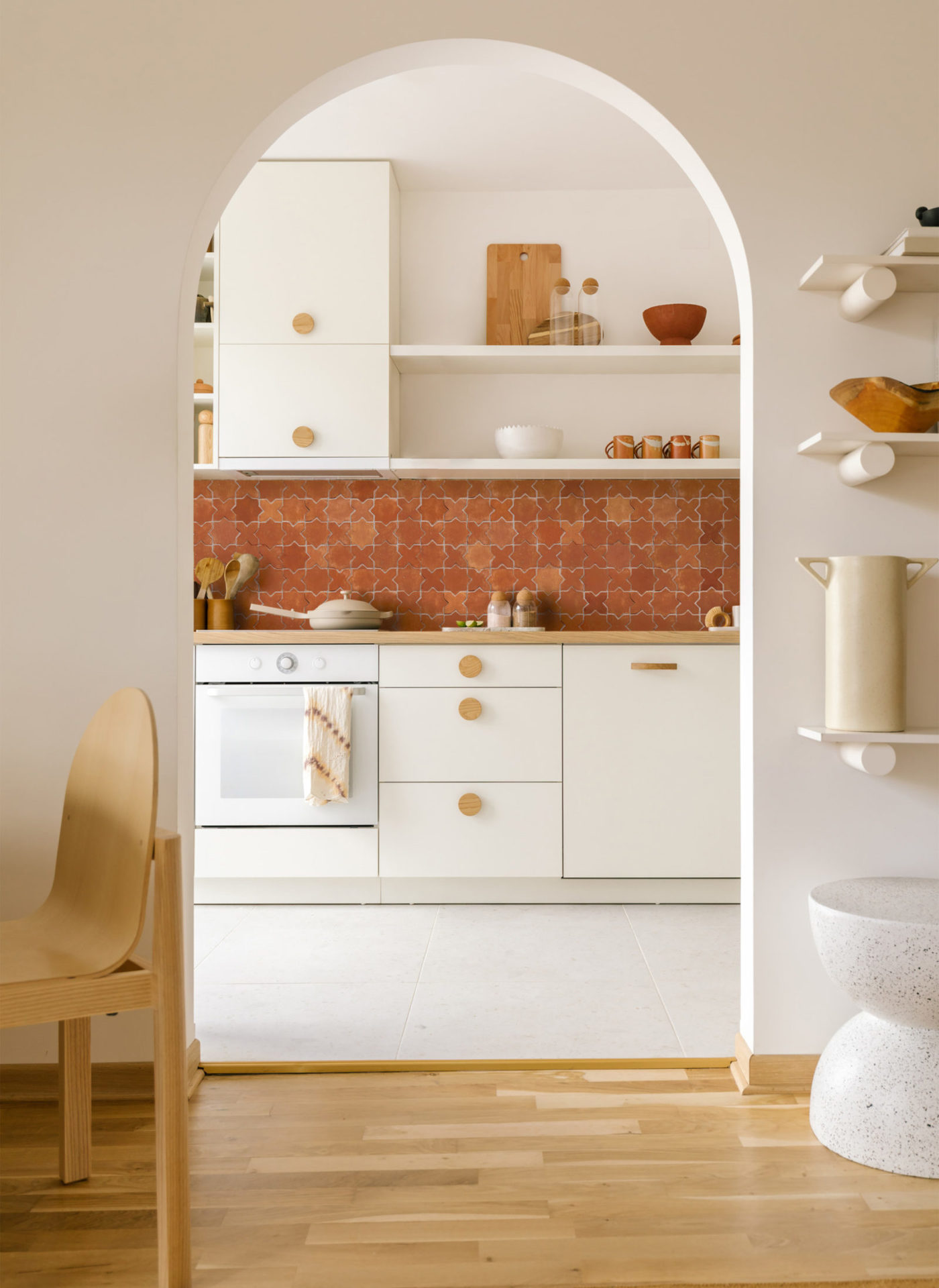 a kitchen with a wooden floor and red tiled backsplash.