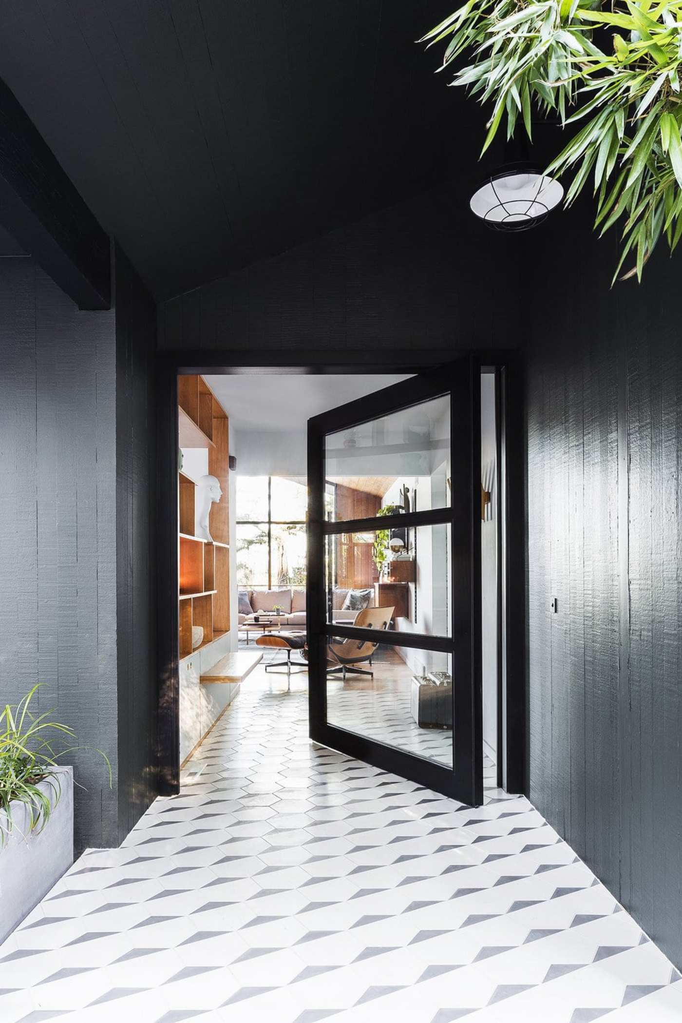 an entryway with a black door and white tiled floor.