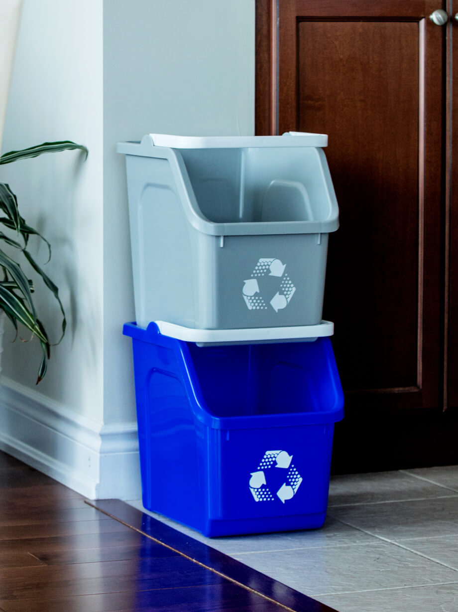 stackable blue and grey handheld recycling bins with white handle and printed mobius loop icon sitting on kitchen floor
