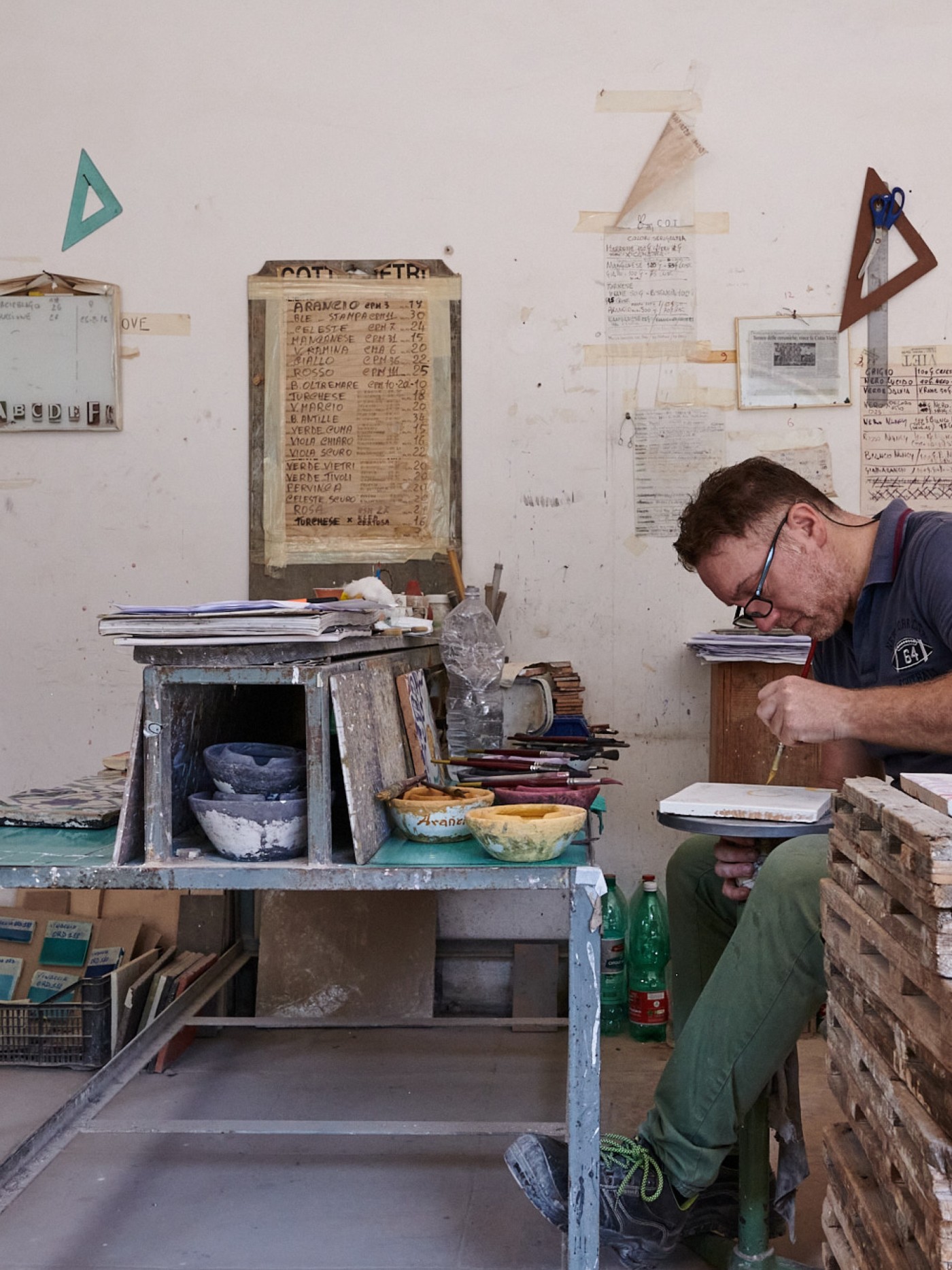 a man painting tile in an art studio.