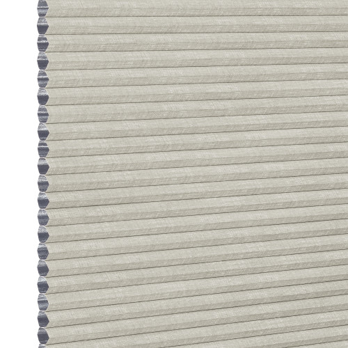 Light beige honeycomb cellular shade with pleated fabric and exposed hexagonal cell ends at left, fully lowered and closed, concealing view; close-up product-style shot on white background with even lighting.