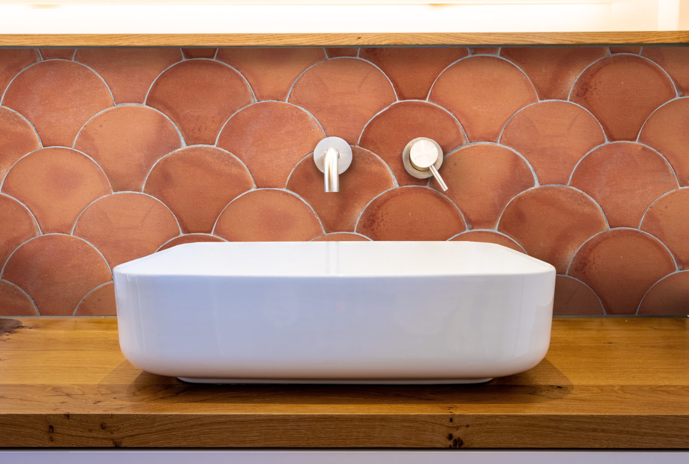 a white sink in a bathroom with a red tiled backsplash.