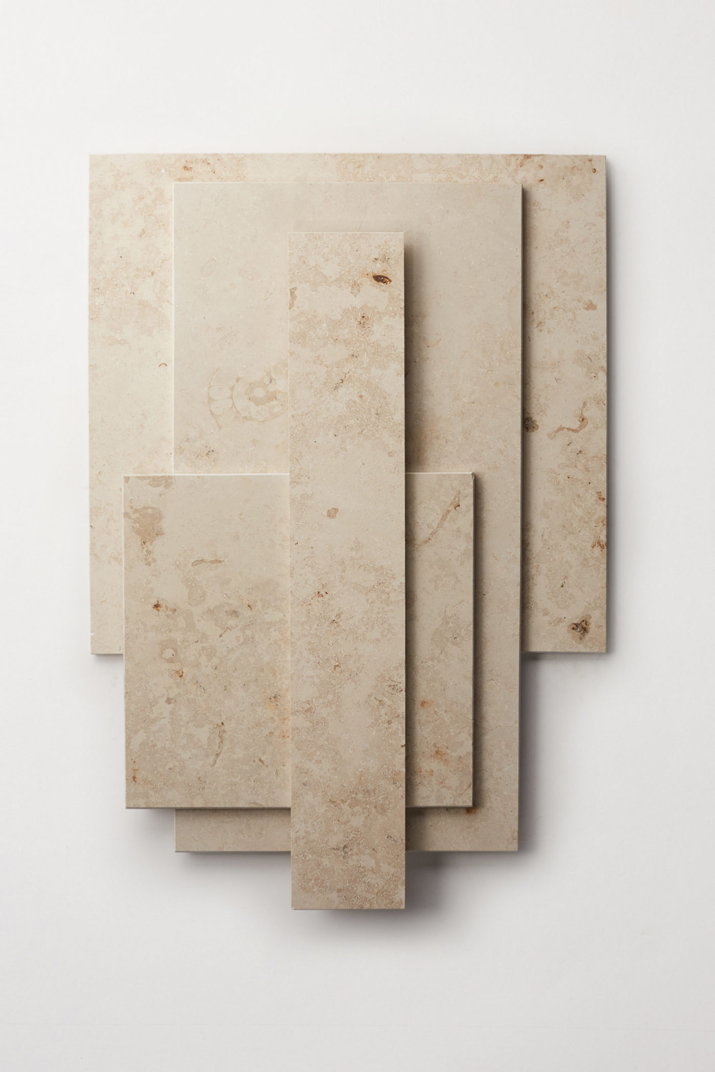 a stack of various sized limestone tiles on a white surface.