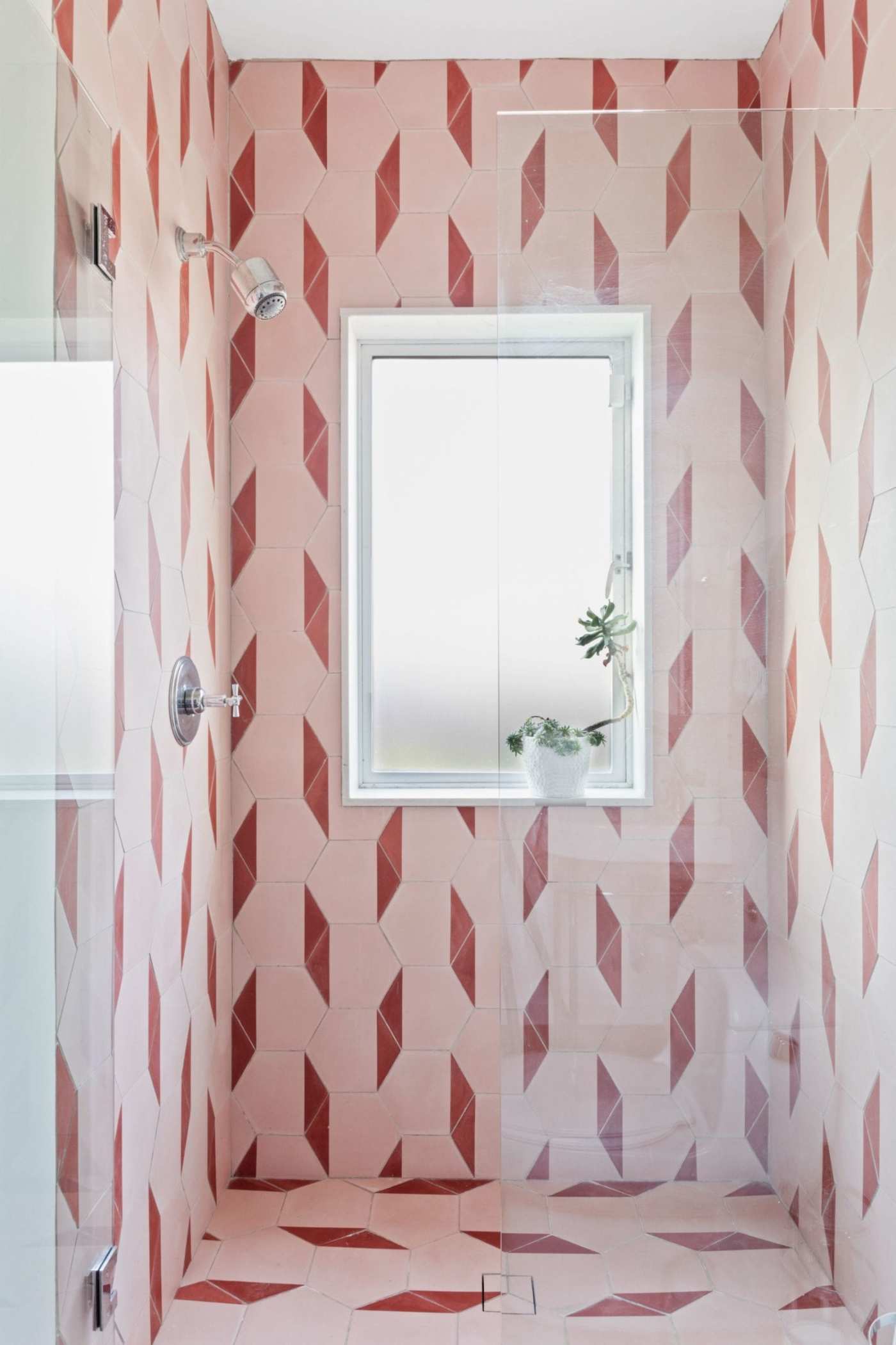 a pink and red tiled shower with a window.