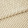 Textured beige-and-cream fabric with raised rectangular stripe pattern, folded once and layered, shown close-up on a neutral surface under soft, even studio lighting.
