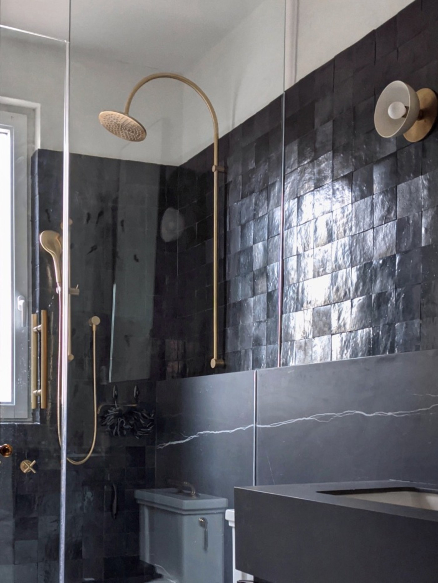 a black tiled bathroom with a glass shower.