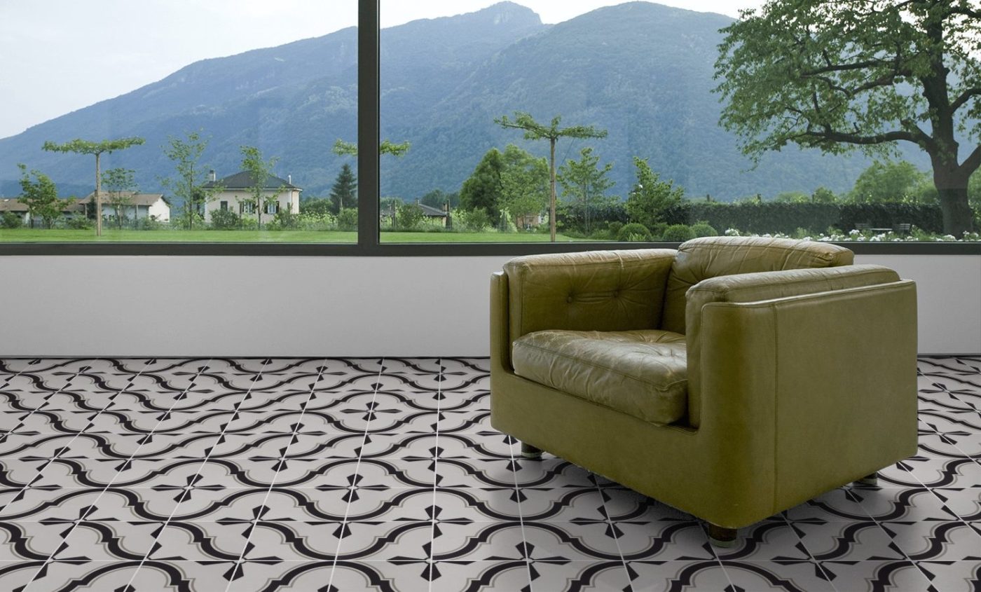 a green chair on a black and white tiled patio with mountains in the background.