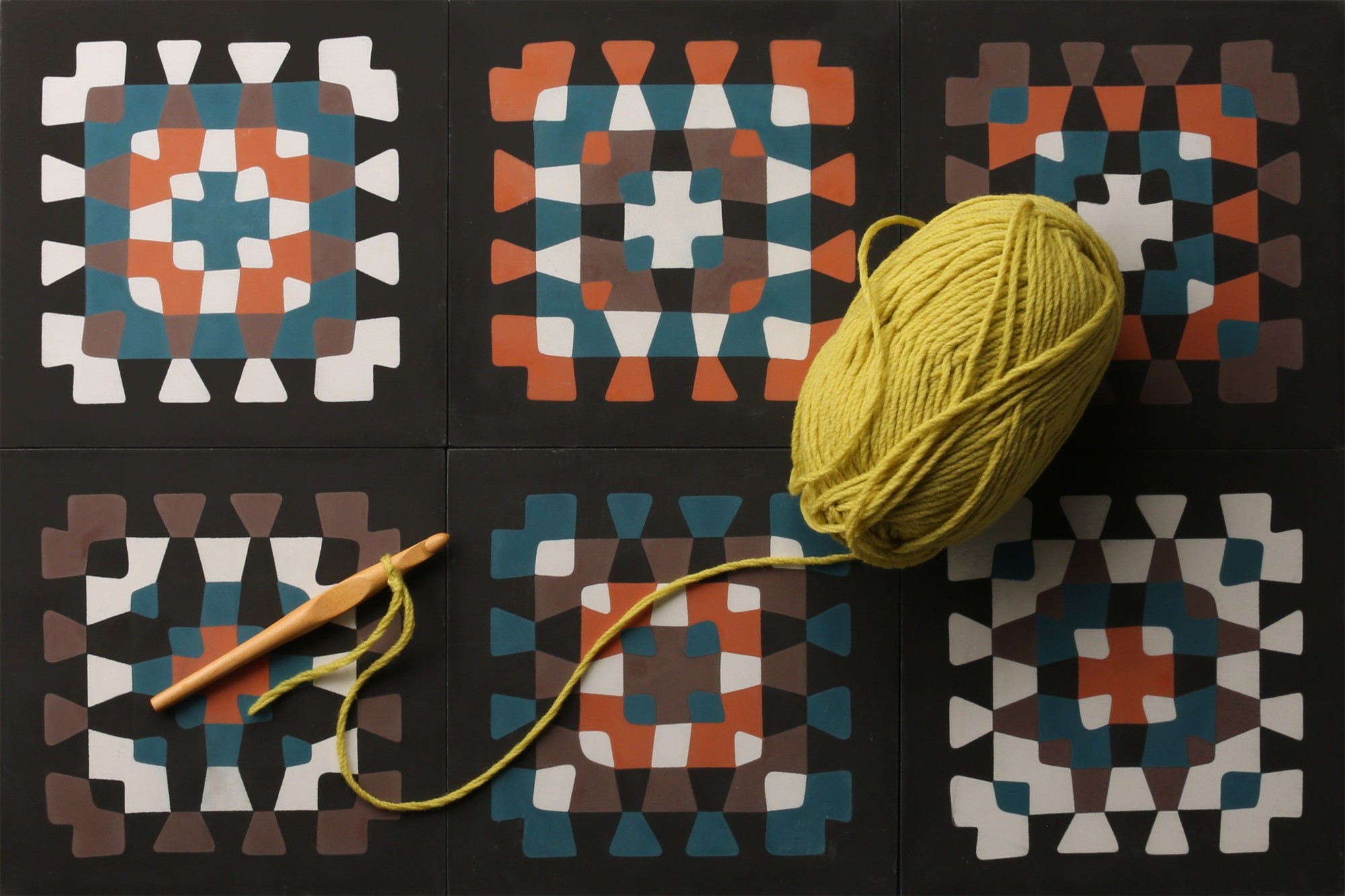 a yellow spool of yarn on top of six abstract tiles.