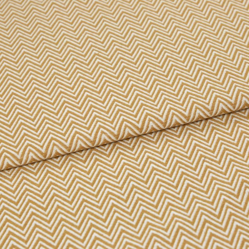 Mustard-and-white chevron fabric, tightly woven, folded across the frame; pattern repeats in narrow zigzags. Close-up view showing textured weave and soft, even lighting on a flat surface.