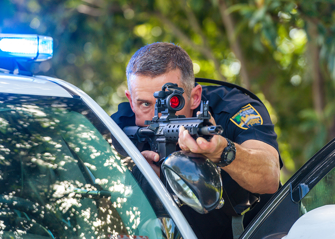 Law enforcement officer aiming an Aimpoint-equipped rifle