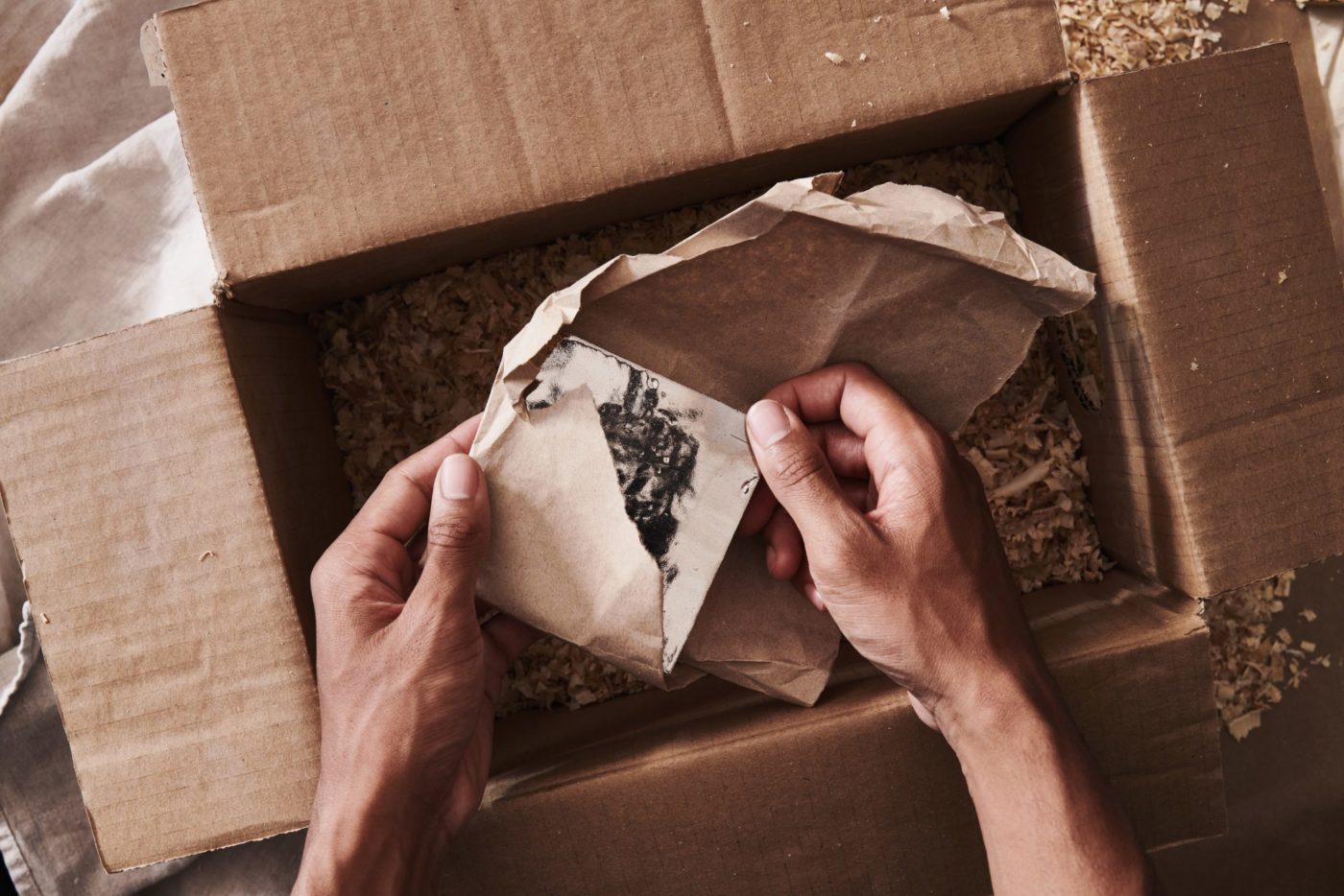 a person opening a cardboard box with a tile inside.