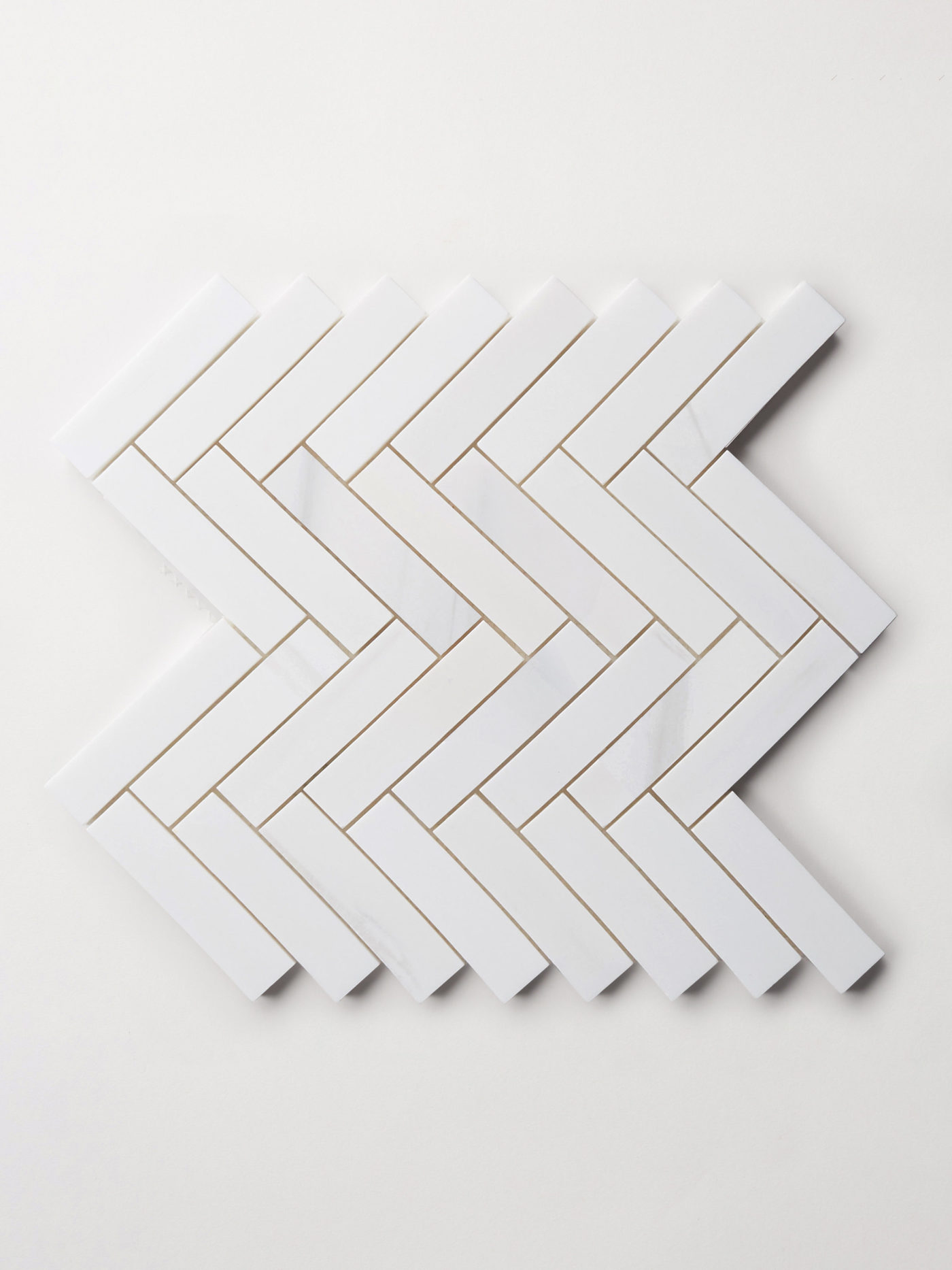 a set of white rectangle tiles arranged in a herringbone pattern on a white surface.