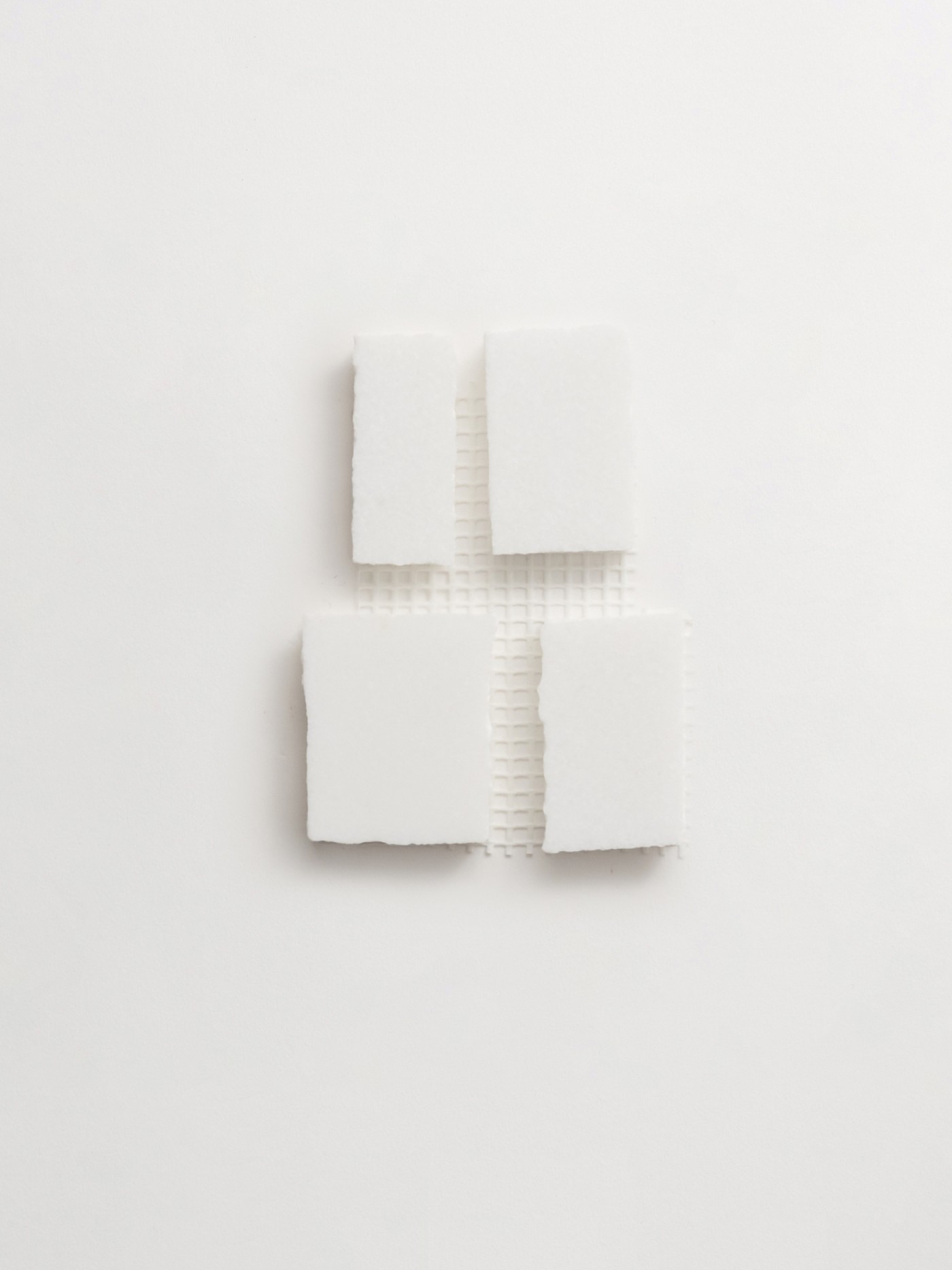 four squares of white soap on a white surface.