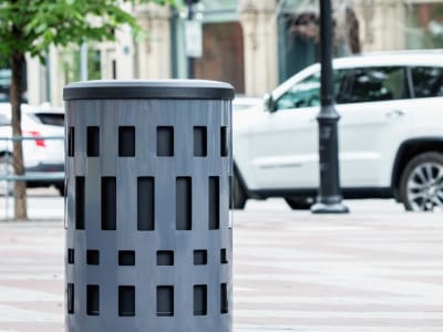 grey powder coated steel waste and recycling container with a durable plastic lid at a busy city intersection
