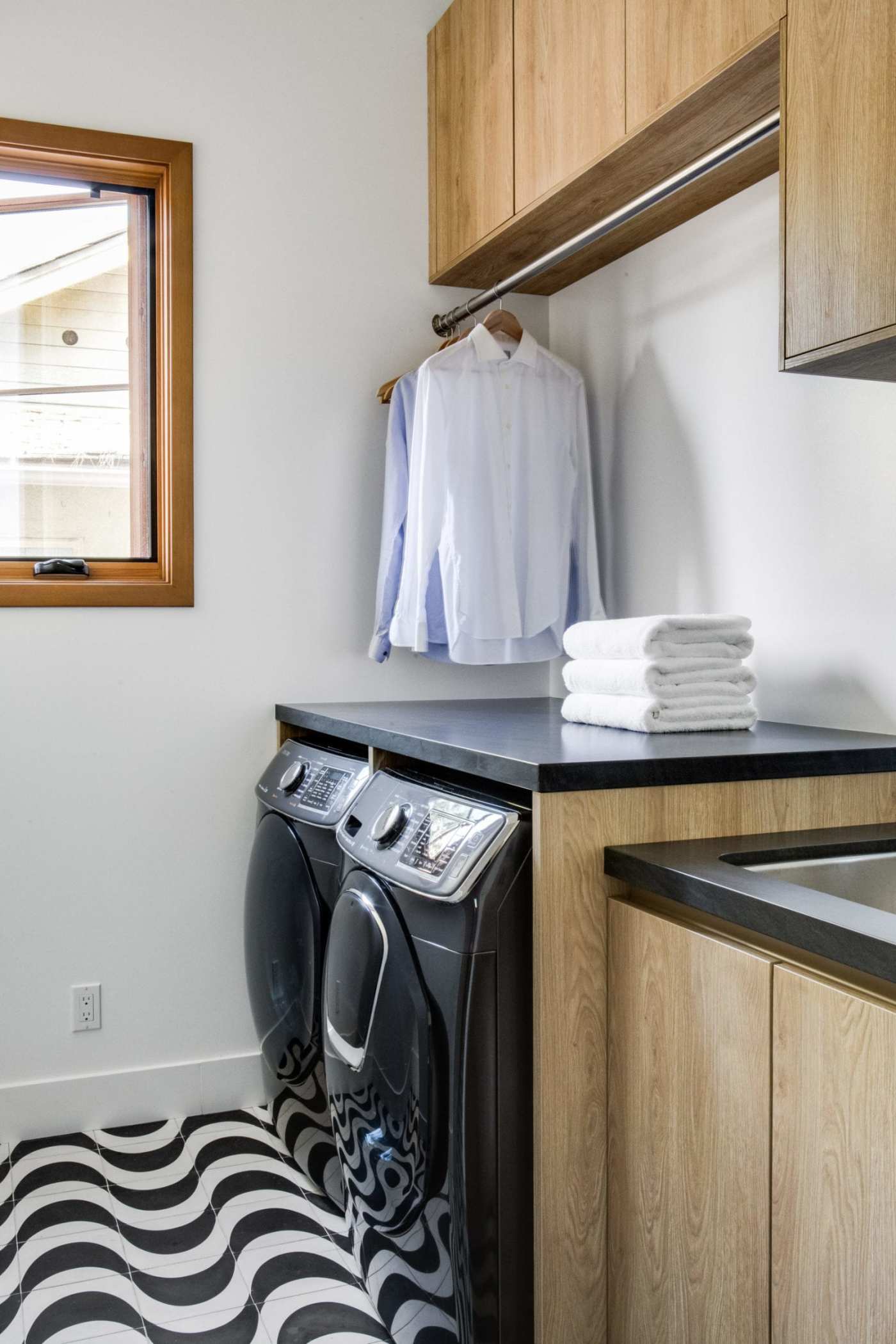 a laundry room with a black and white tiled floor and a washer and dryer.