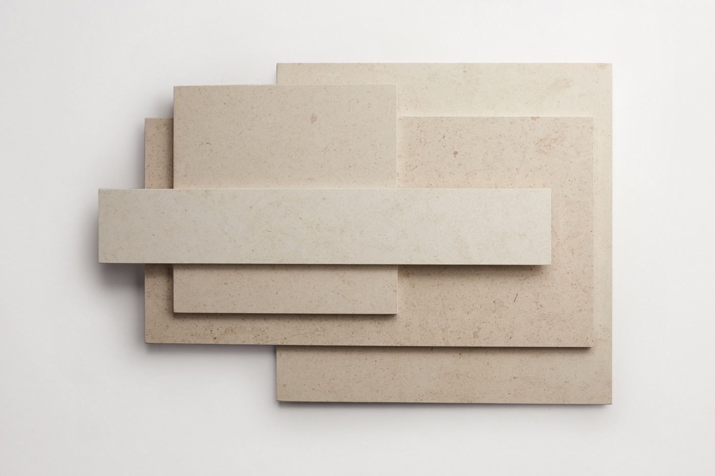 a stack of various sized limestone tiles on a white surface.