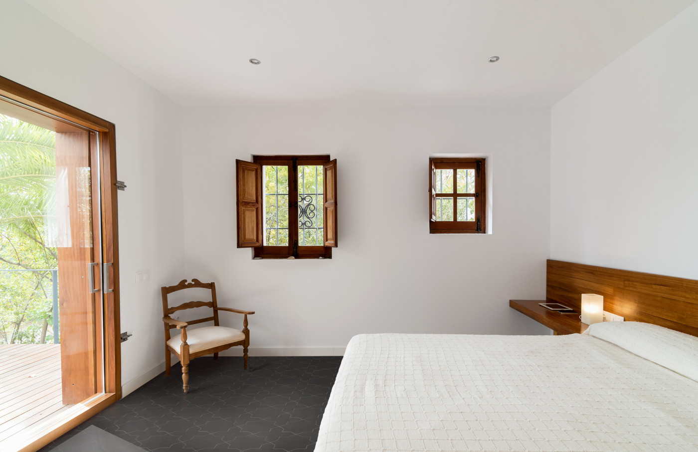 a white bed in a bedroom with a black tile floor.