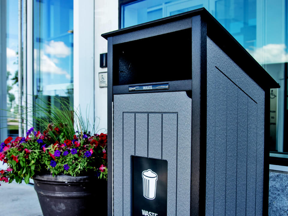 black and grey waste bin made from recycled plastic sitting outside at the entrance to a condo