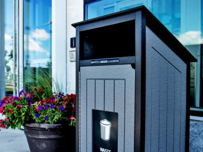black and grey waste bin made from recycled plastic sitting outside at the entrance to a condo