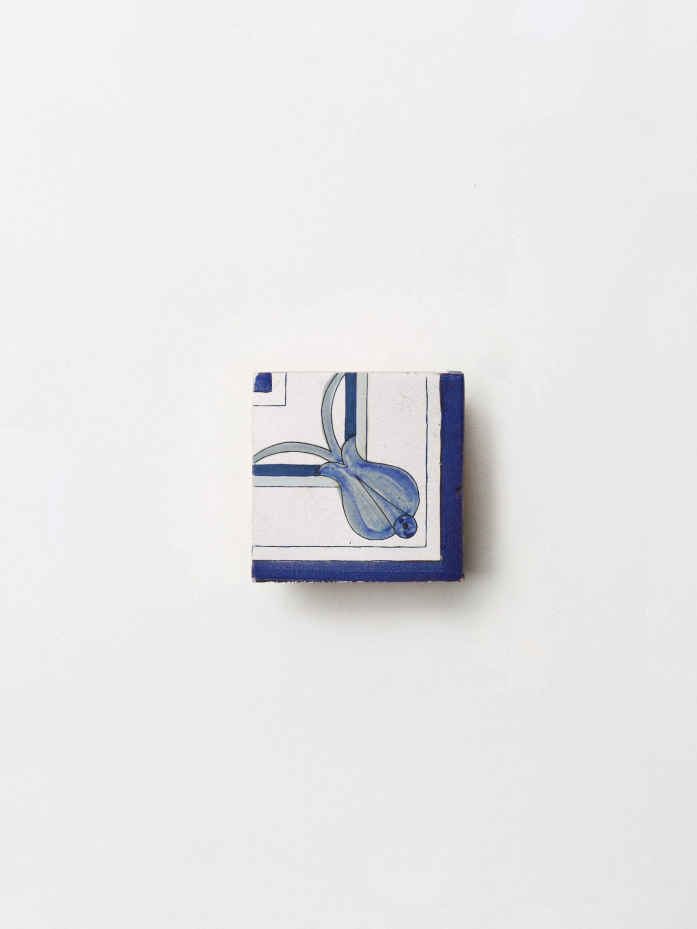 a blue and white hand painted tile on a white surface.