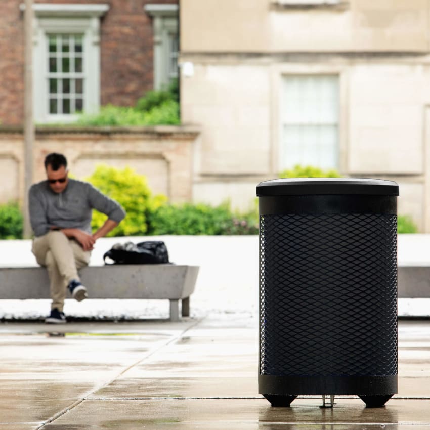 Metal body outdoor trash bin with plastic black liner and lid to help improve collection sitting outside a corporate office