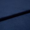 Navy-blue soft fabric, folded into overlapping layers creating a diagonal ridge and subtle shadow, showing a fine, slightly nappered texture; close-up studio view with soft, even lighting.