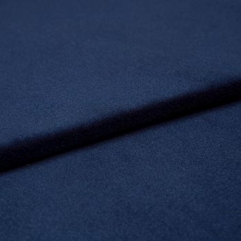 Navy-blue soft fabric, folded into overlapping layers creating a diagonal ridge and subtle shadow, showing a fine, slightly nappered texture; close-up studio view with soft, even lighting.