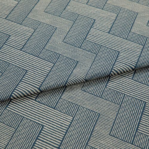 Blue-and-cream woven fabric with interlocking rectangular striped pattern, partially folded and layered, showing raised texture and seam â€” close-up on a flat surface under soft studio lighting.